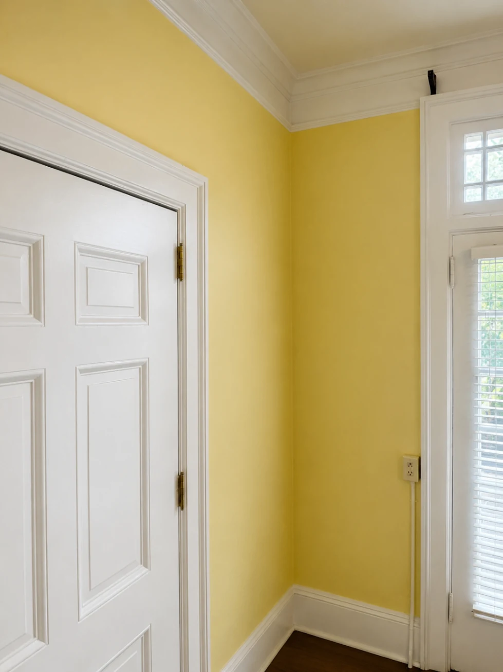 Completed yellow interior wall painting with white trim