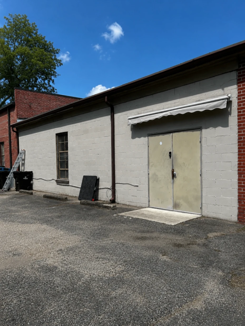 Exterior building before painting with gray cinderblock walls and metal double doors